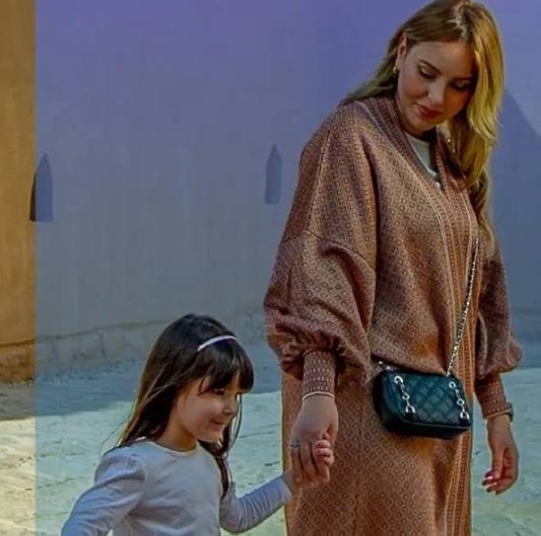 International visitors spend nearly SR50 billion in Saudi Arabia during 1Q 2025 A woman in a patterned abaya walking hand in hand with a young girl, outdoors on a sunny day.